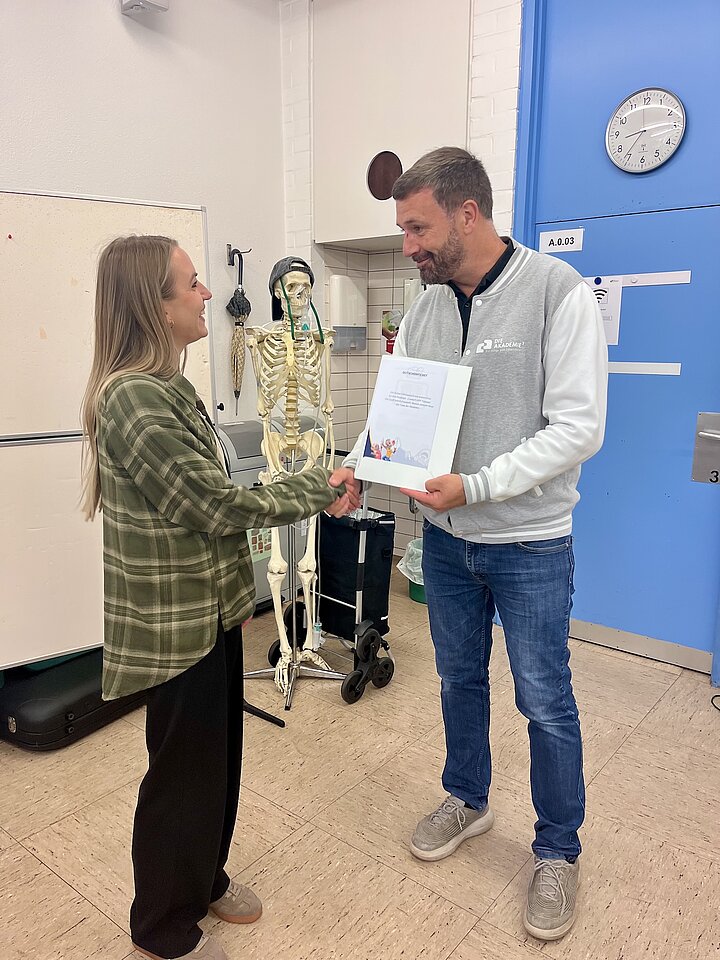 Andreas Heck, Geschäftsführer der AKADEMIE², gratuliert Angelika Drozdz per Handschlag zu ihrem Sieg beim WM-Kicktipp der AKADEMIE²
