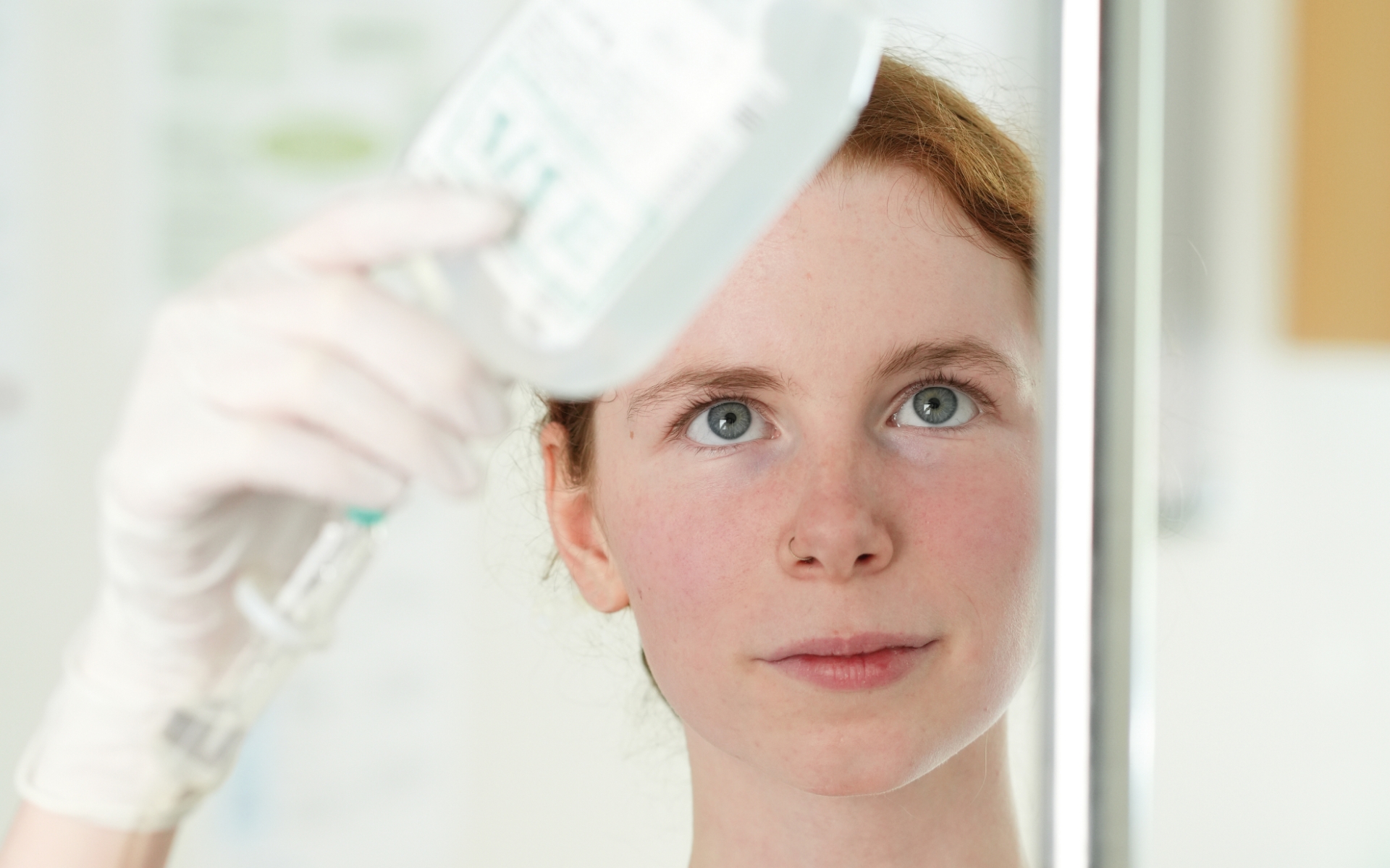 Mit voller Konzentration: Ronja richtet eine Infusion – denn in der Pflege zählt jeder Handgriff. Junge Azubildende in der Pflege mit Handschuhen fixiert eine Infusion