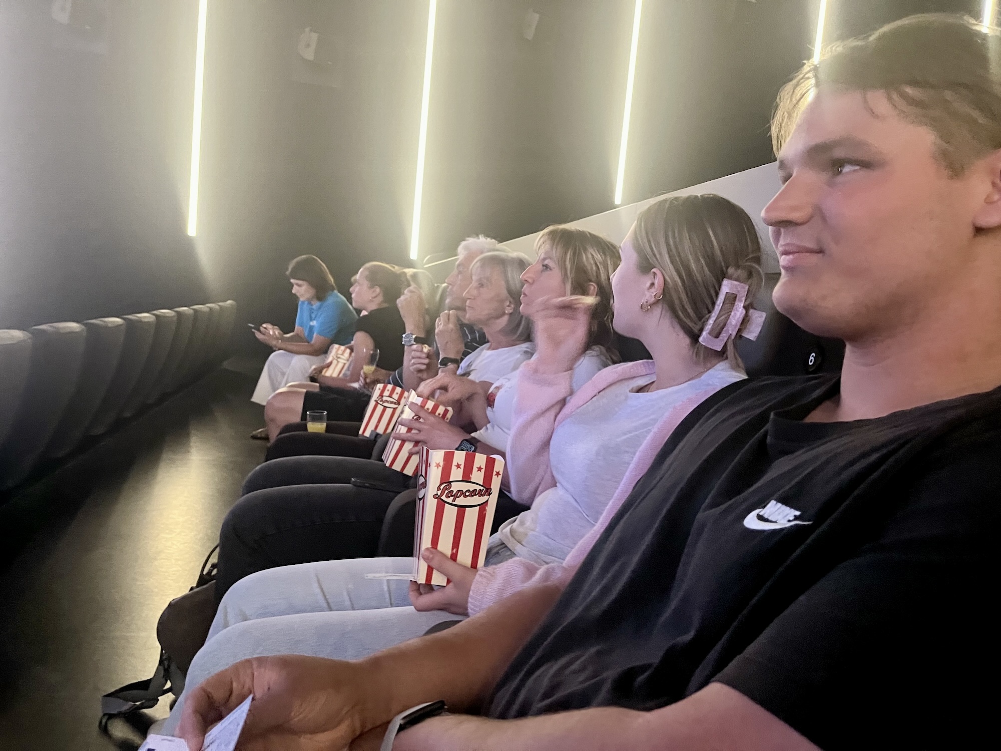 Auszubildende und Mitarbeitende der AKADEMIE² warten im ForumKino Offenburg auf den Start des Kinospots. Foto: AKADEMIE²
